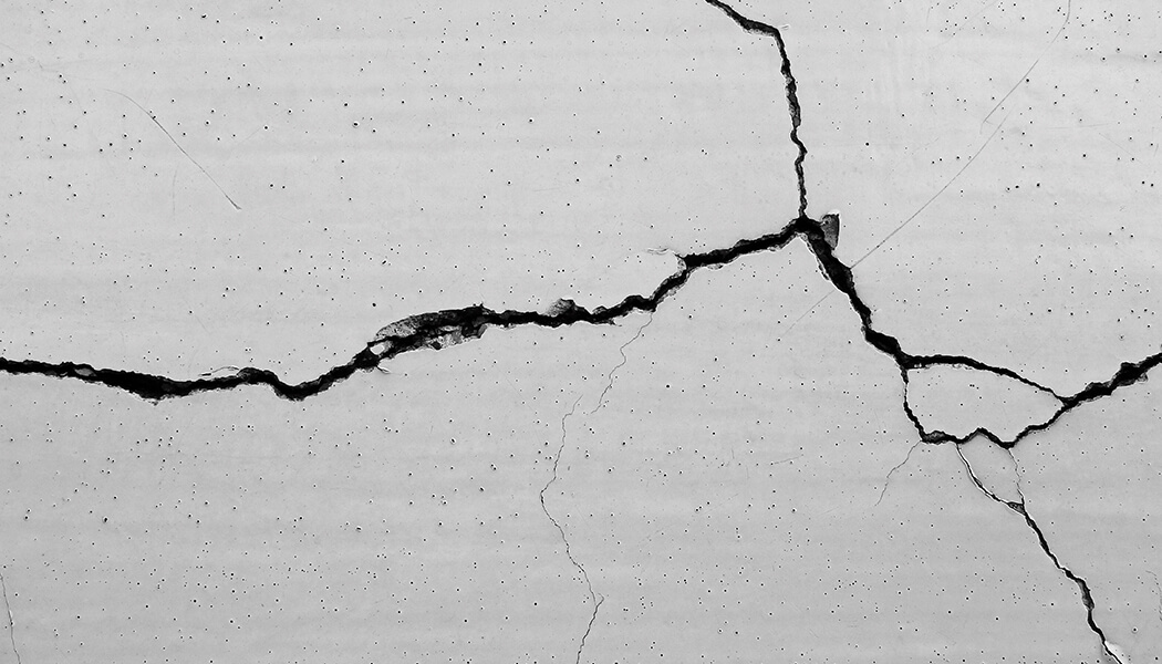 Up close of white wall with completely spread deep crack from foundation damage